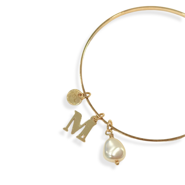 Dettaglio bracciale rigido con iniziale e perla di cristallo