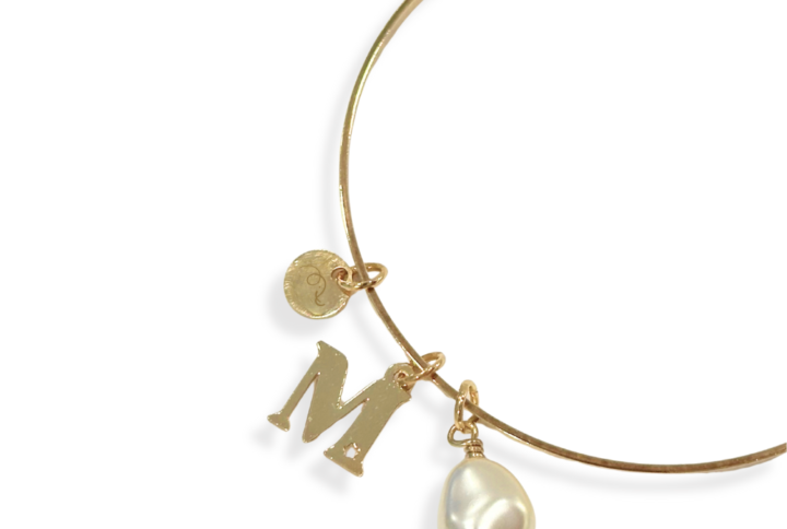 Dettaglio bracciale rigido con iniziale e perla di cristallo